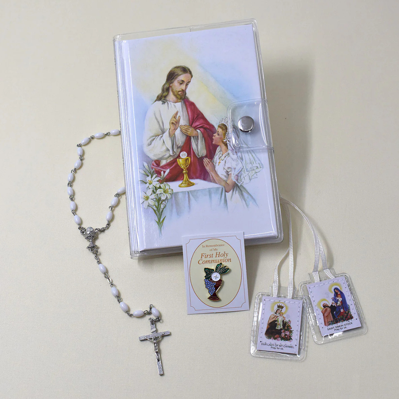 Religious items including a rosary, prayer cards, and a Holy Communion book on a light background