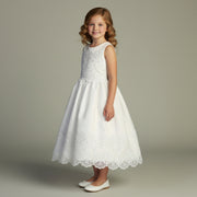 Young girl wearing a white lace First Communion dress against a neutral background