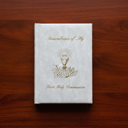White book titled 'Remembrance of My First Holy Communion' on a wooden surface