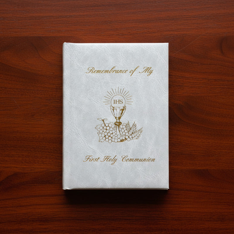 White book titled 'Remembrance of My First Holy Communion' on a wooden surface