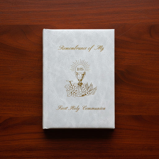 White book titled 'Remembrance of My First Holy Communion' on a wooden surface