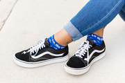 Person wearing blue St. Joan of Arc socks with a fleur-de-lis print