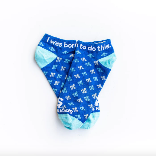A pair of blue and white St. Joan of Arc socks with a quote printed on the ankle area that says 'I was born to do this'.