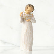 A figurine of a woman with a gold necklace holding a heart-shaped pendant, saying 'I love you'.