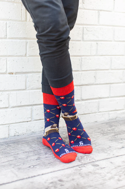 Person wearing blue and red patterned socks with St. Augustine and flaming hearts, on a wooden floor.