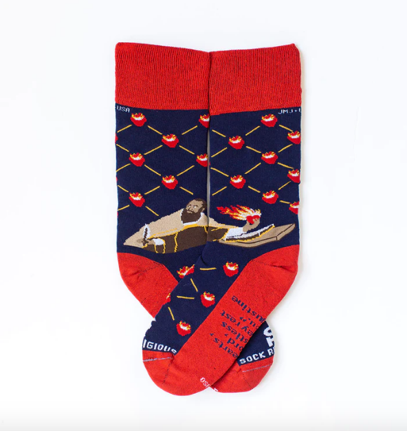 Person wearing blue and red patterned socks with St. Augustine and flaming hearts, on a wooden floor.