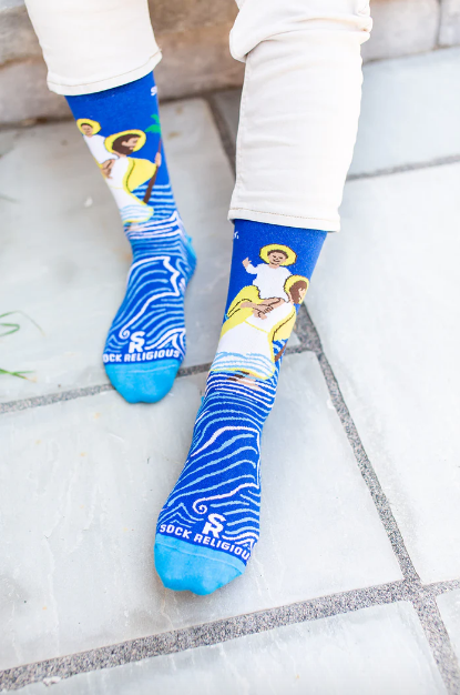 Person wearing blue socks with images of St. Christopher carrying the Infant Jesus through water