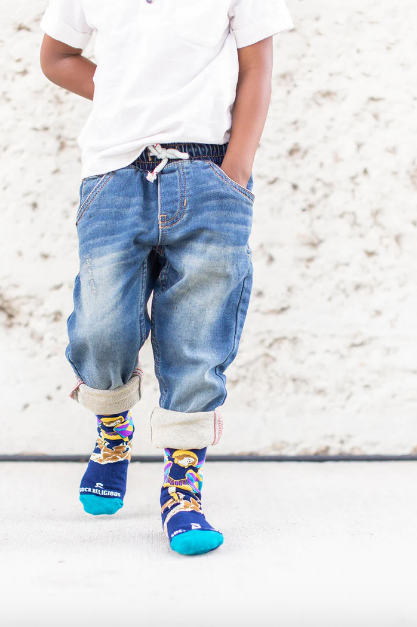 Colorful socks with images of St. Michael the Archangel worn by a child on a light background
