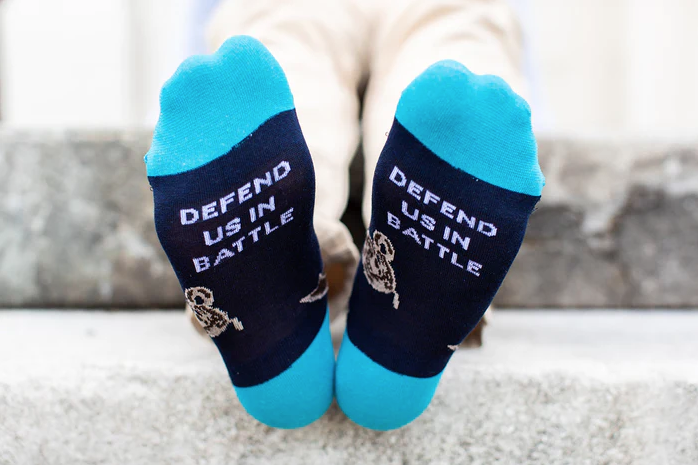 Colorful socks with images of St. Michael the Archangel worn by a child on a light background