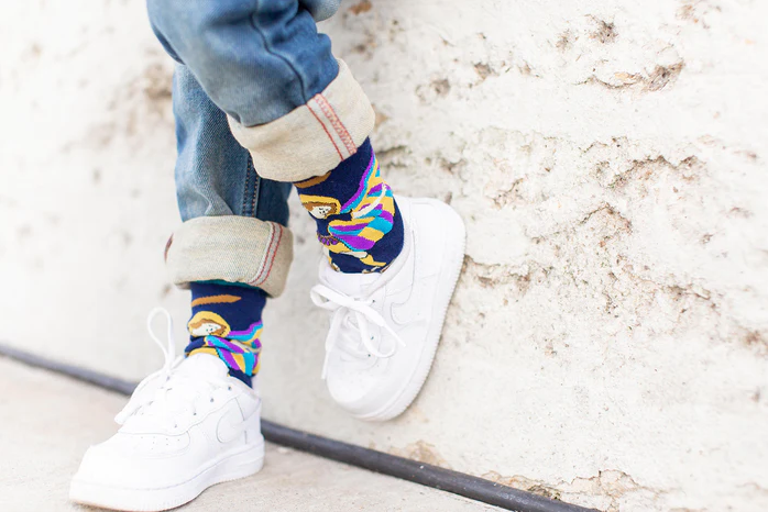 Colorful socks with images of St. Michael the Archangel worn by a child on a light background