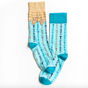 Light blue St. Peregrine-themed socks with text and cross designs on a white background