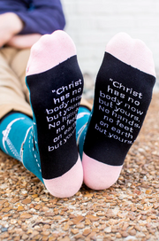 Person wearing blue socks featuring an image of St. Teresa of Avilia and the Holy Spirit