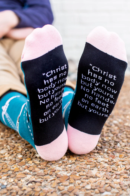 Person wearing blue socks featuring an image of St. Teresa of Avilia and the Holy Spirit