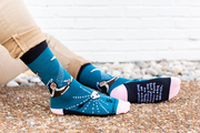 Person wearing blue socks featuring an image of St. Teresa of Avilia and the Holy Spirit