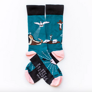 A pair of socks with a design featuring St. Teresa of Avila, with colors including blue, black, pink, and white, and various symbols and text related to the saint.