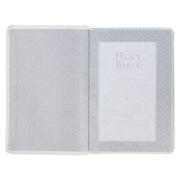 A white faux leather compact Bible with a quatrefoil floral design on a white background.