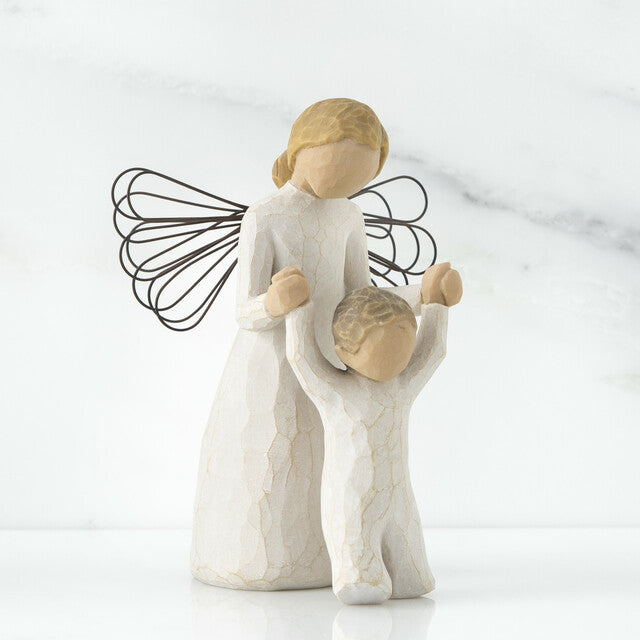 A figurine of a guardian angel, with a resin and metal construction, depicted in a praying posture alongside a child.